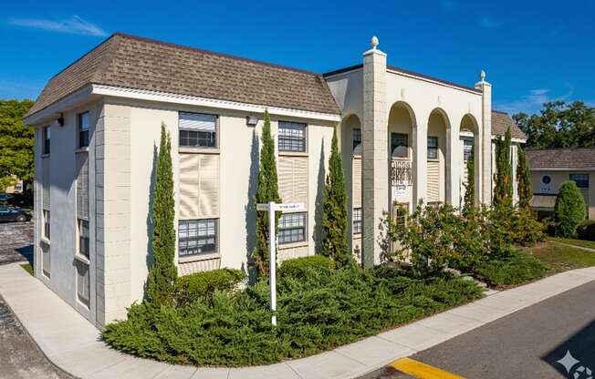 A white building with a brown roof and a yellow line on the road in front of it.