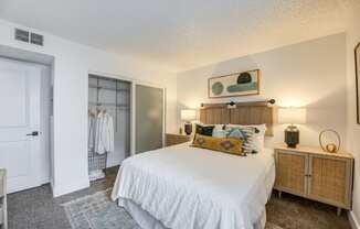 Fusion Warner Center one bedroom apartment in Woodland Hills carpeted bedroom with frosted glass doors on closet and large bed with white boho duvet.