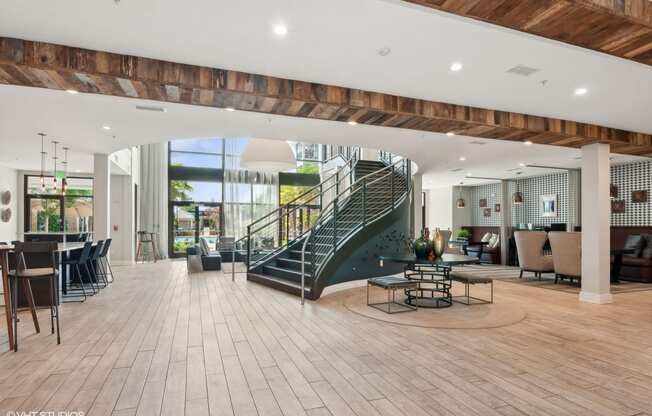 a spiral staircase in the lobby of a building with tables and chairs