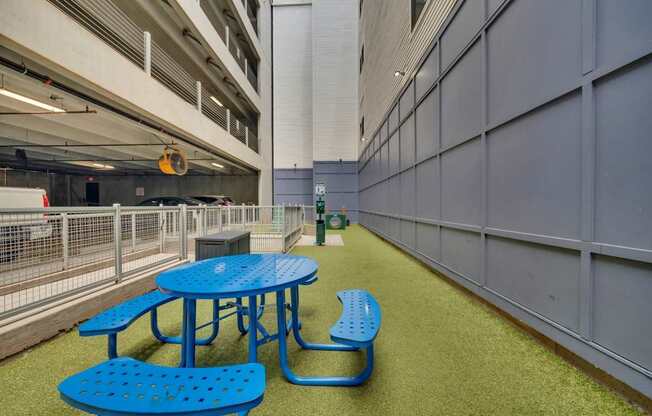 A blue picnic table and bench are in a parking garage.
