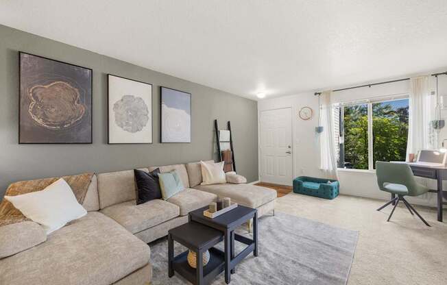 A living room with a beige couch, a coffee table, and a green pet bed at Clackamas Trails Apartments, Oregon, 97222