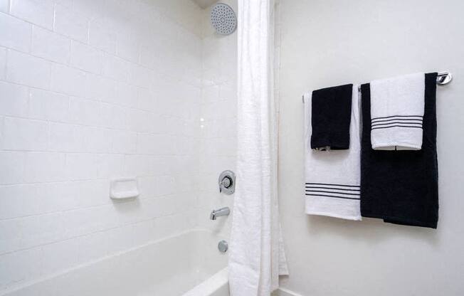 A white bathroom with a shower and towel rack.