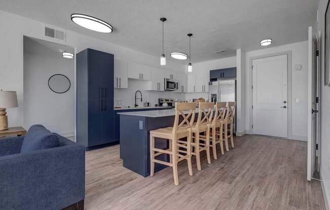 A kitchen with a blue couch and wooden chairs.