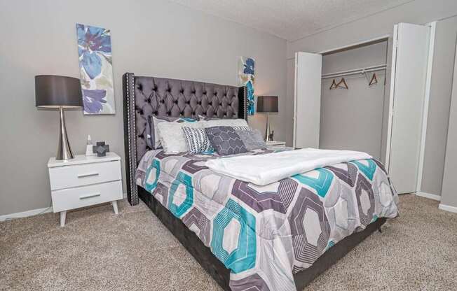 Model bedroom with a large bed and a white nightstand at Maplewood apartments in Shreveport, LA.