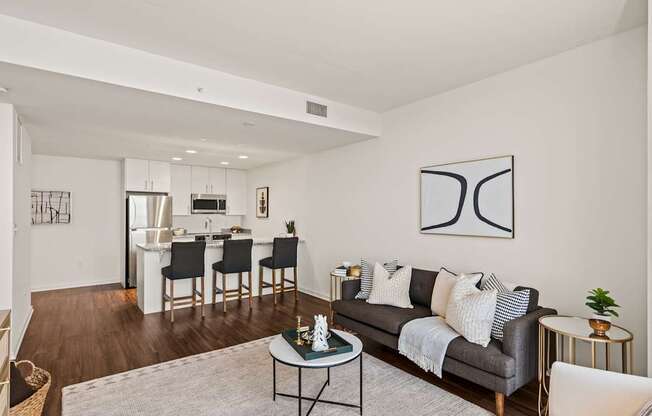 A modern living room with a grey couch, a coffee table, and a dining table with chairs.