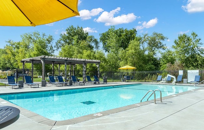 A sunny day at the pool with a yellow umbrella providing shade.