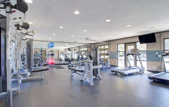 a spacious fitness center with cardio equipment and a pink exercise ball
