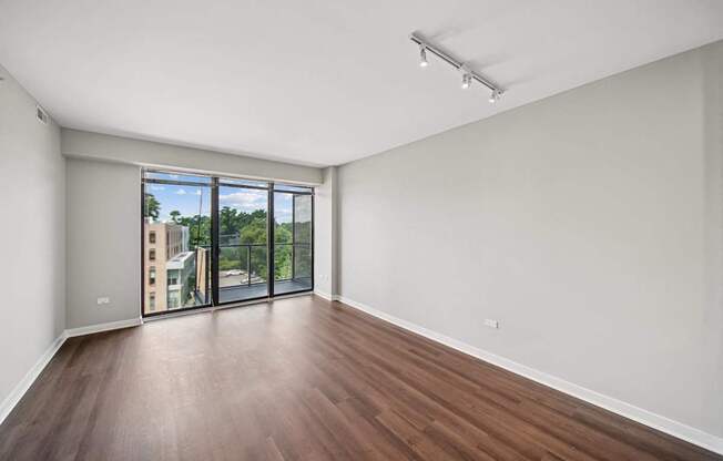 A room with wooden floors and a sliding glass door leading to a balcony.