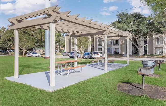 A white pergola with a picnic table underneath it.