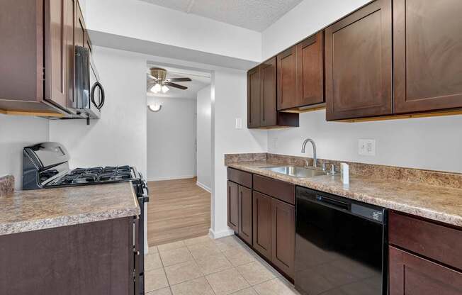 A kitchen with brown cabinets and a black dishwasher.