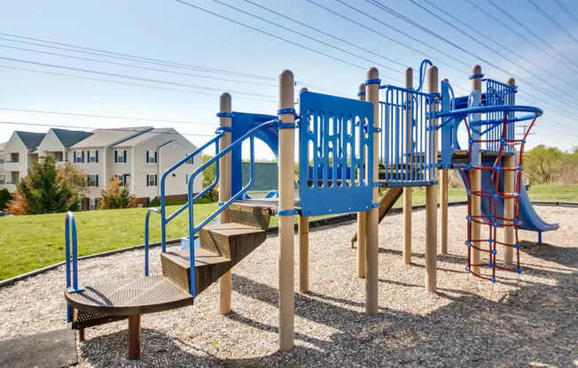 A playground with a blue slide and a wooden structure.