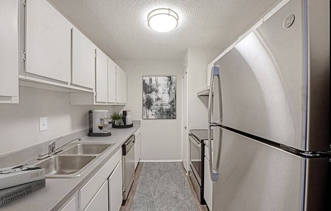 Galley style kitchen with white cabinets and stainless steel appliances  at The Waverly, Belleville, Michigan