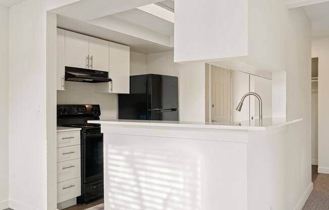 A kitchen with a large l-shaped breakfast bar, white top and bottom cabinets, and upgraded appliances.