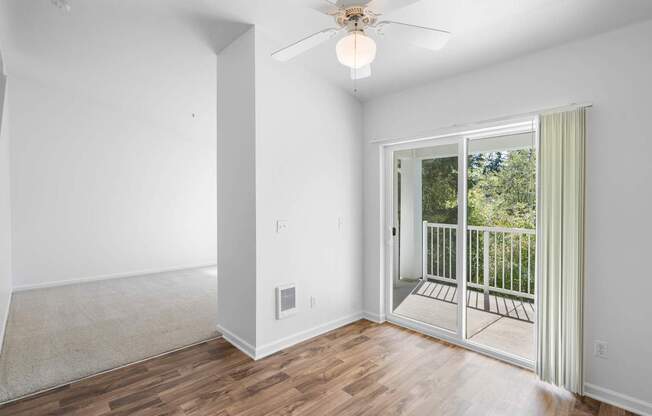 a living room with white walls and a sliding glass door to a balcony