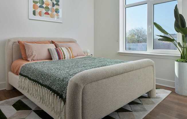 A bed with a green blanket and a white pillow is in the image.