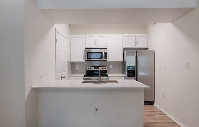 a kitchen with white cabinets and stainless steel appliances