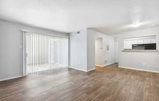 the living room of an apartment with a large window and wood flooring