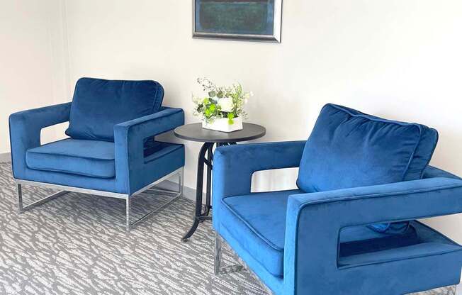 Two blue chairs and a small table with flowers on it.