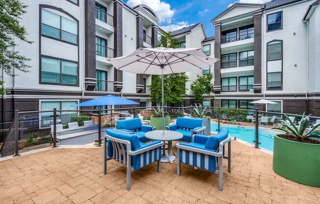 an outdoor patio with chairs and umbrellas and a swimming pool