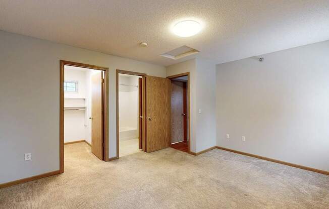 A room with a carpeted floor and three doors.