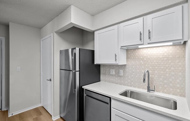 a kitchen with white cabinets and a stainless steel refrigerator at Highland Park Apartment Homes, Overland Park