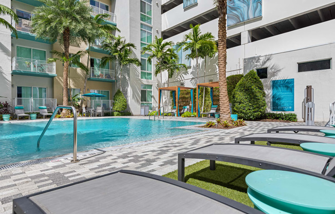 a swimming pool in front of a building with palm trees