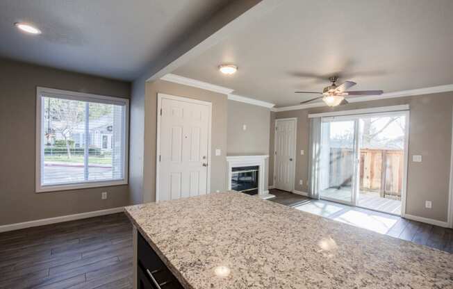 View from kitchen bar top into living room with fireplace and access to private balcony/patio through sliding glass door, with well lit window