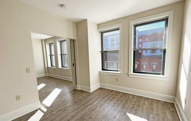 a bedroom with hardwood flooring and three windows