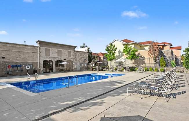 The community heated swimming pool with a row of custom sun loungers behind the clubhouse at The Residences at Toscana Park in Granger, Indiana.
