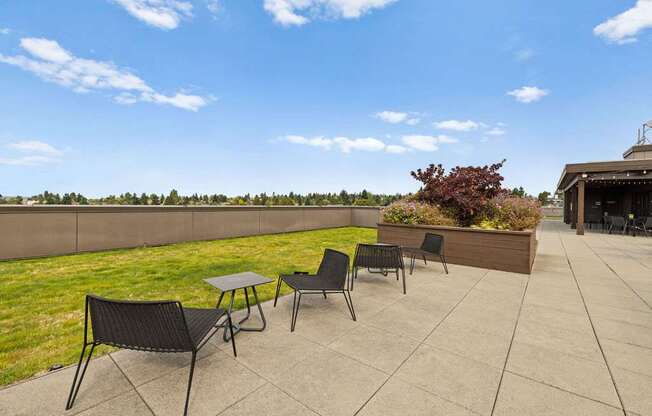 A patio with a table and chairs overlooking a grassy field.