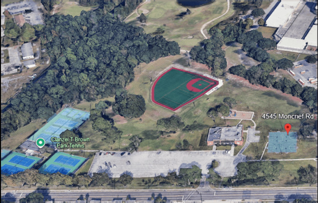 An aerial view of a baseball field surrounded by trees and other buildings.
