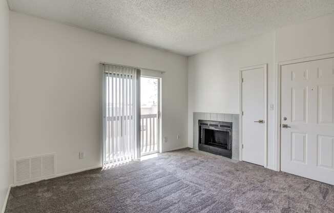 an empty living room with a fireplace and sliding glass doors