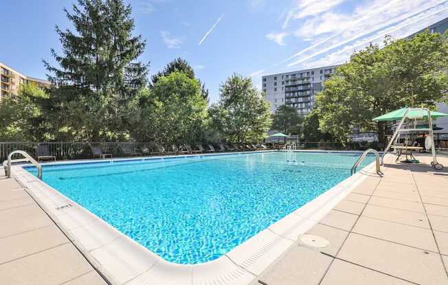 A large swimming pool surrounded by trees and a building in the background.