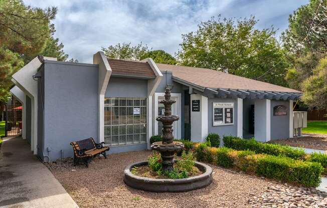 A grey building with a fountain in front of it.