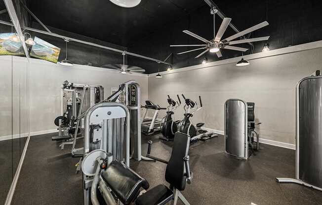A gym with a variety of equipment including a weight bench, a leg press machine, and a rowing machine.