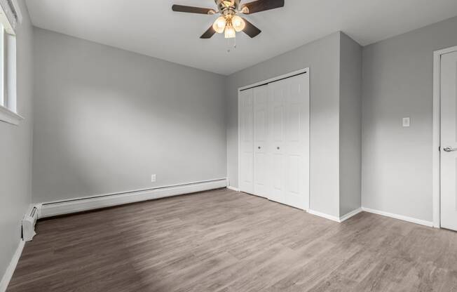an empty living room with a ceiling fan and a closet