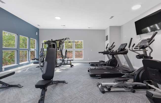 an exercise room with cardio equipment and a tv