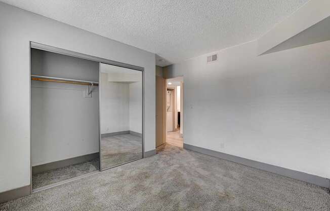 A room with a white wall and a grey carpet.