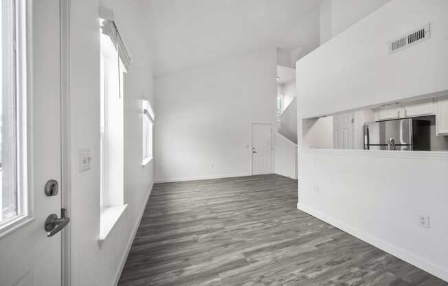 an empty living room with a kitchen in the background