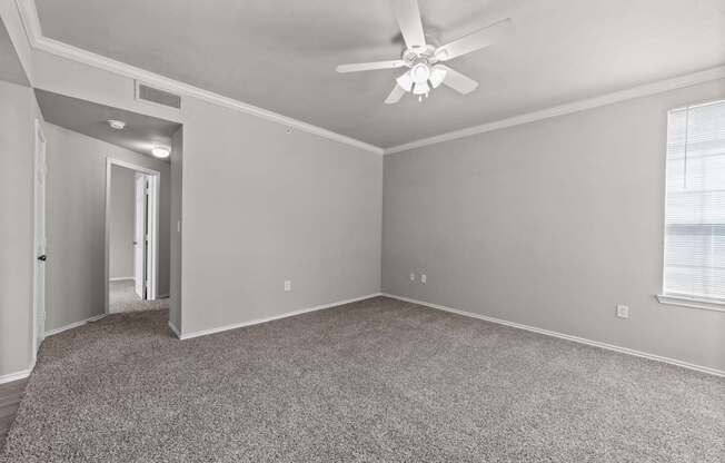A room with a ceiling fan and carpeted floor.