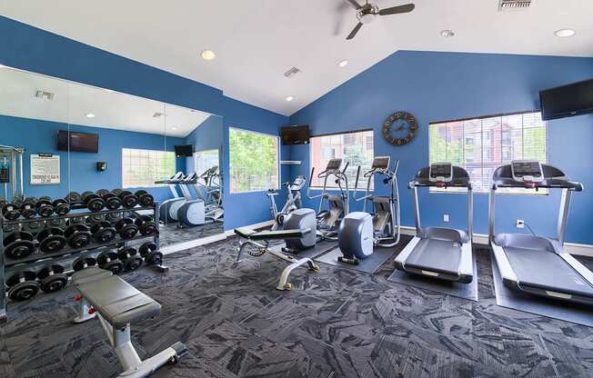 A gym with a variety of equipment including treadmills, weights, and exercise machines.