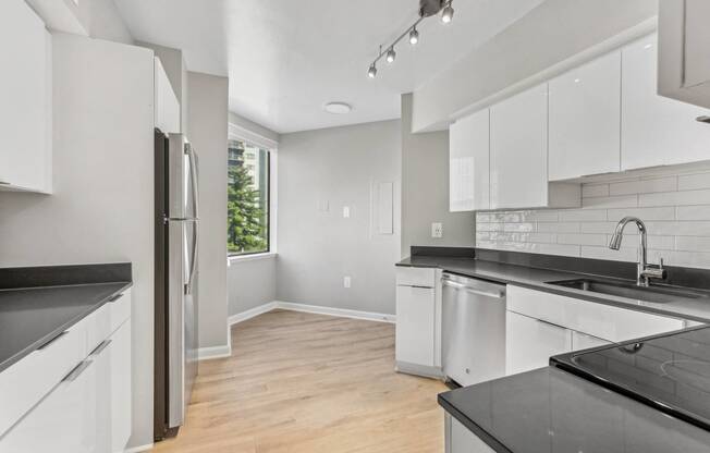 an empty kitchen with white cabinets and black counter tops