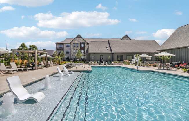 a swimming pool with chairs and a building in the background at The Depot Raymore, MO 64083