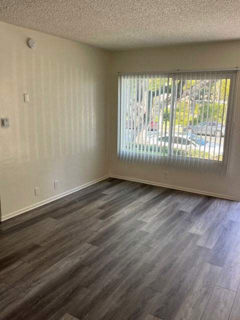 Front room with large window and wood plank style flooring in unit at Los Robles Apartments in Pasadena, California.