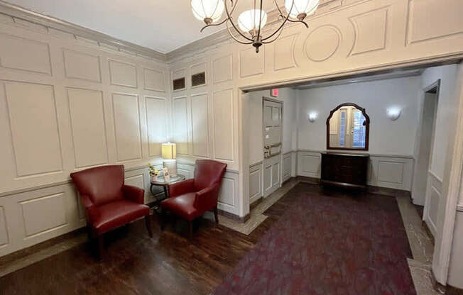A room with a chandelier, two red chairs, and a table with a vase of flowers Integrity Realty, Cleveland, Ohio