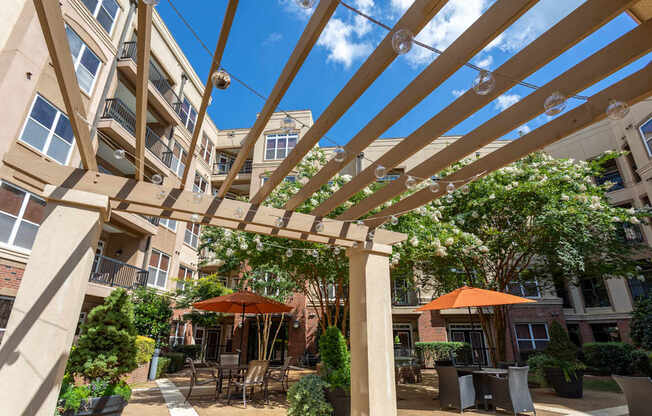 A patio with tables and chairs under a pergola.