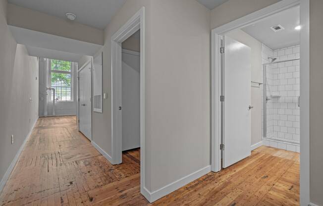 a renovated bedroom and hallway with wood floors and white walls at Spinning Mill Lofts, Clayton, NC 27520