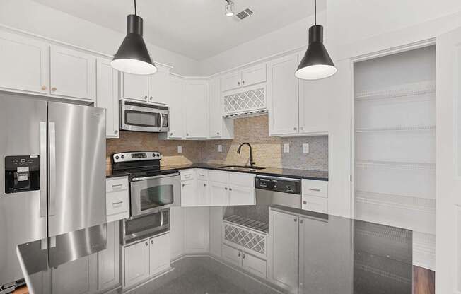 A modern kitchen with stainless steel appliances and white cabinets.