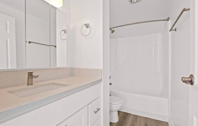 A white bathroom with a sink, toilet and shower.