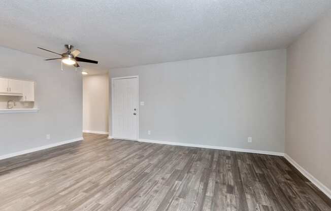 an empty living room with wood floors and a ceiling fan  at Eastwood Crossings, Kansas City, MO